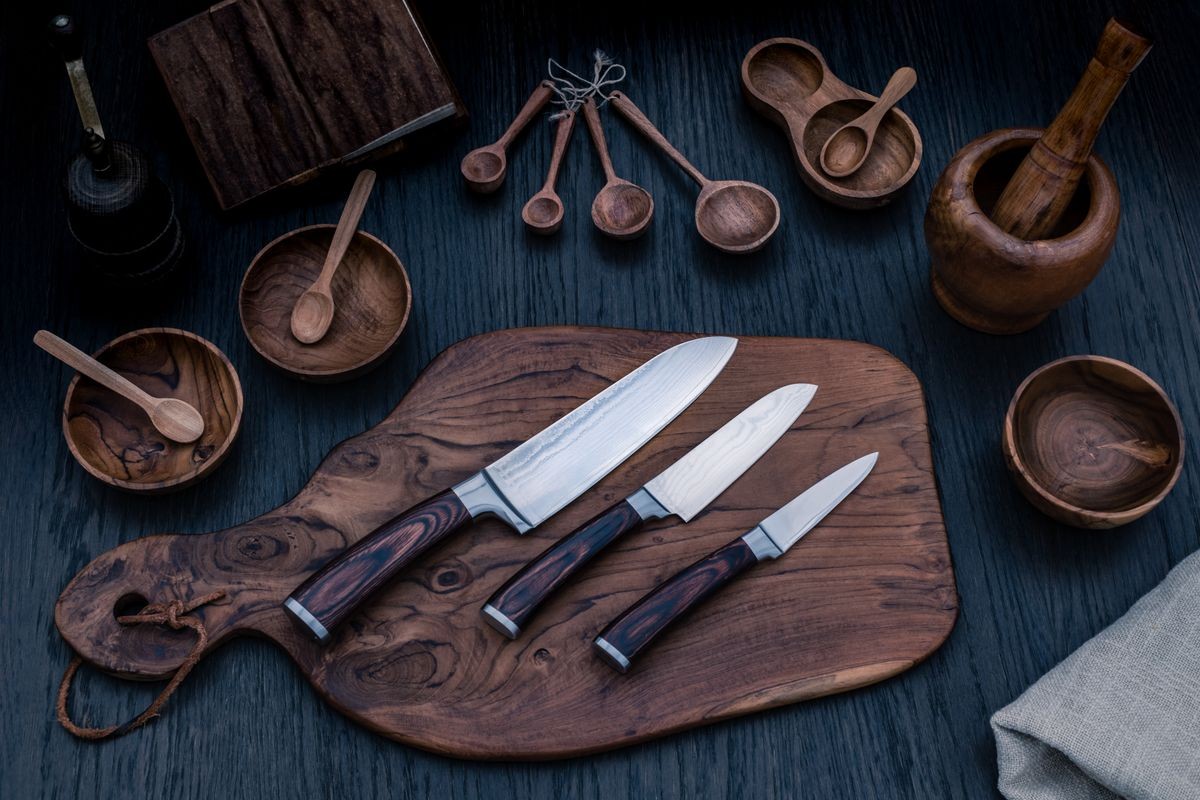 Damascus kitchen steel Knives, Wooden kitchen cutting Board, wooden kitchen measuring spoons,   Recipe Book. Kitchen Utensils background with Santoku damascus steel blade knife